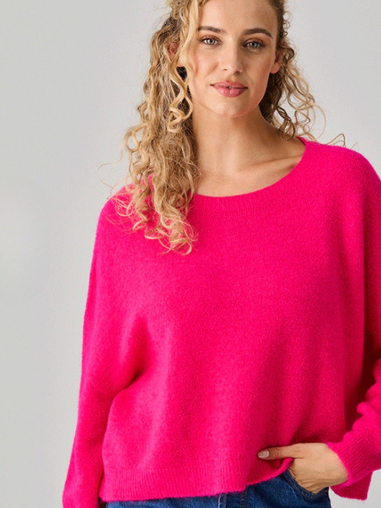 Woman wearing a bright pink sweater against a gray background