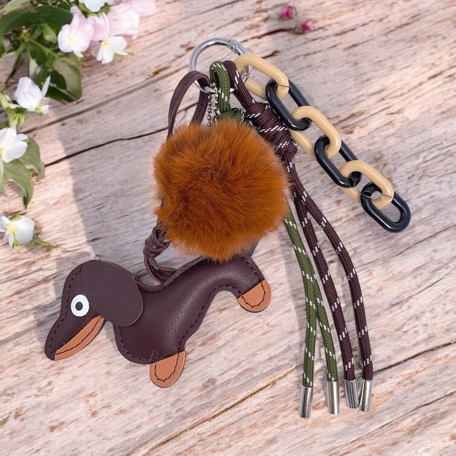 Brown dachshund-shaped keychain with a fluffy pom-pom.