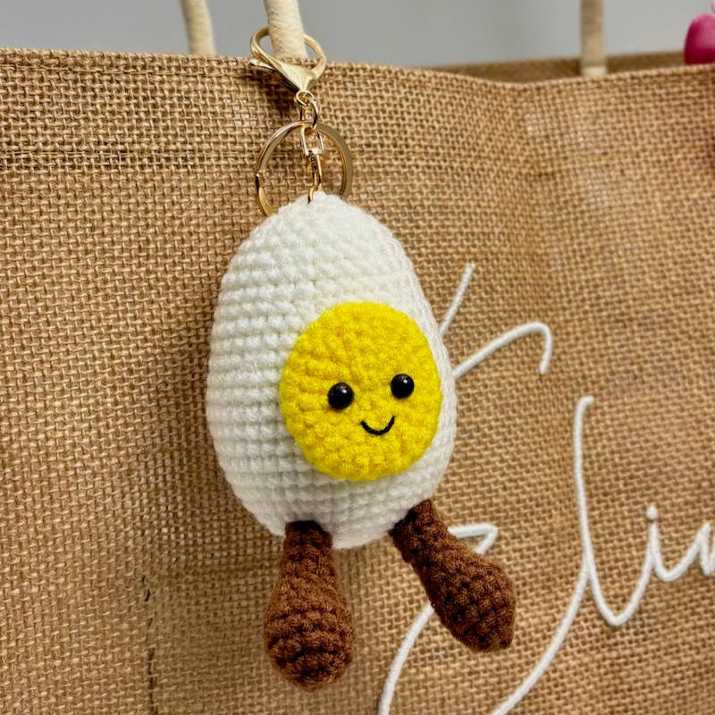 Crocheted egg-shaped keychain with a smiling face