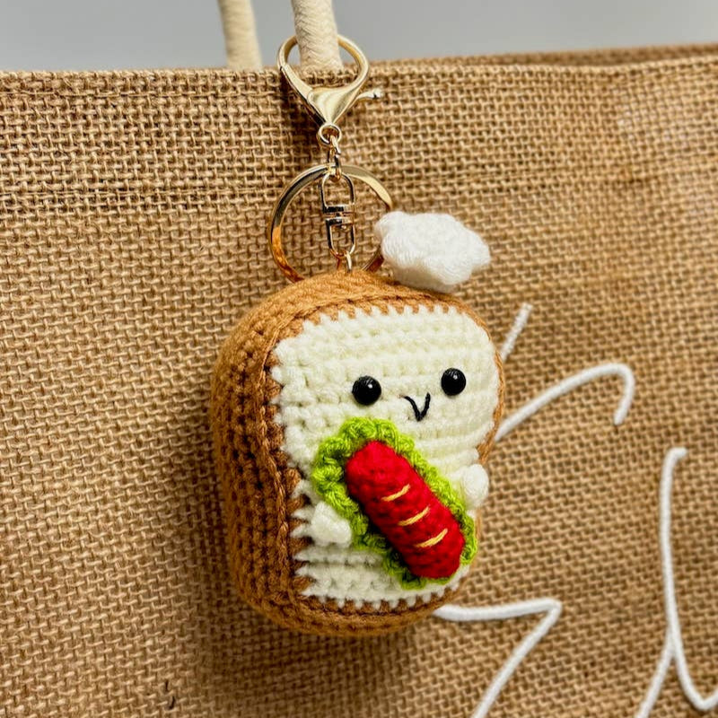 Keychain in the shape of a sandwich with a carrot on a textured beige background