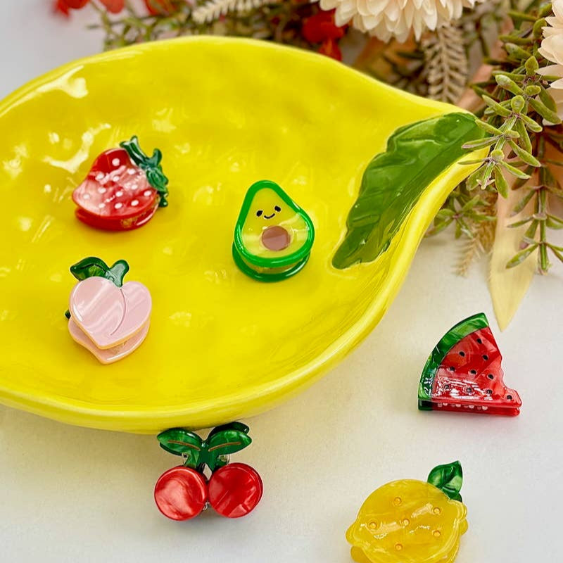 Colorful fruit-shaped earrings on a yellow plate with a floral background
